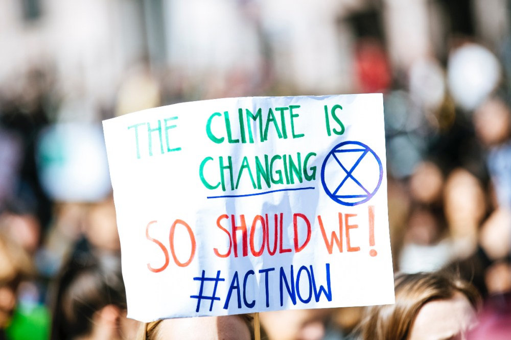 Protest placard saying the climate is changing, so should we with the hashtag act now