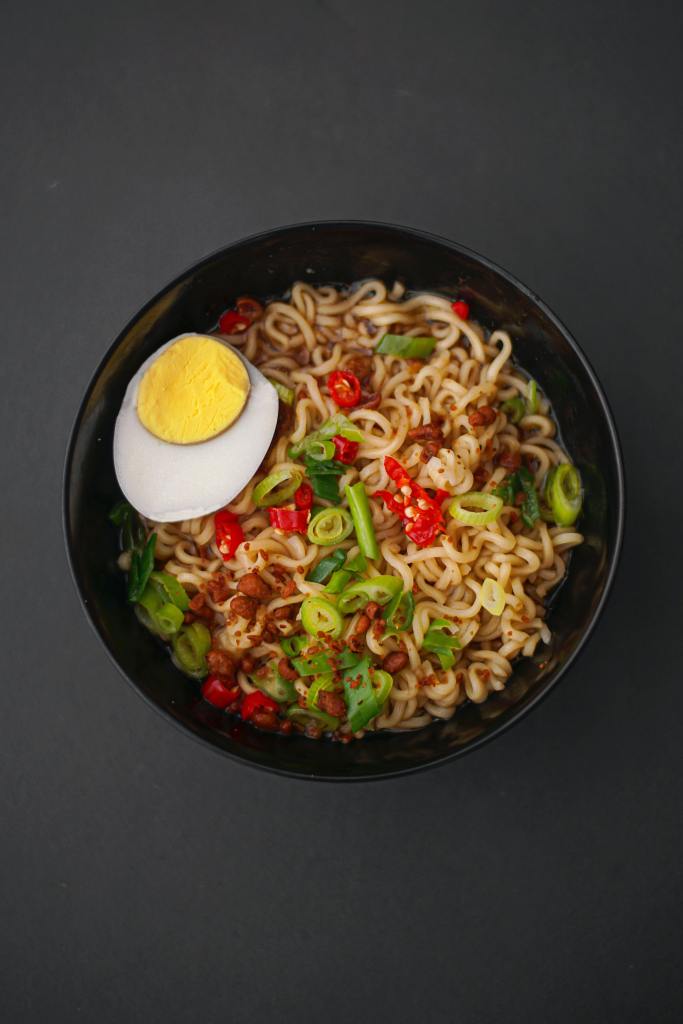 Photo of mushroom ramen noodles with red chili, spring onions and an egg on top