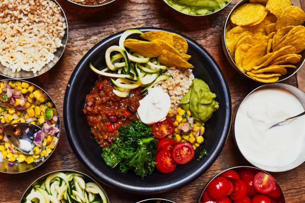 Plant-based chilli spread, including tortilla chips, sour cream, guacamole, tomatoes and sweetwcorn