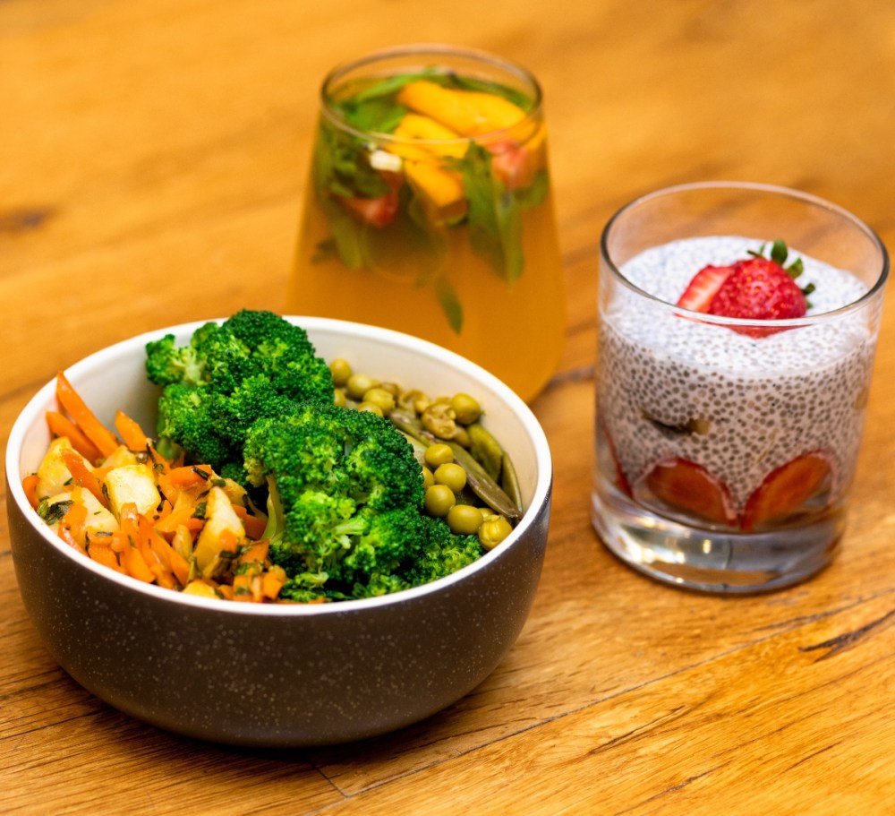 Healthy vegan food including broccoli, carrots, chickpeas and bircher muesli with a strawberry on top